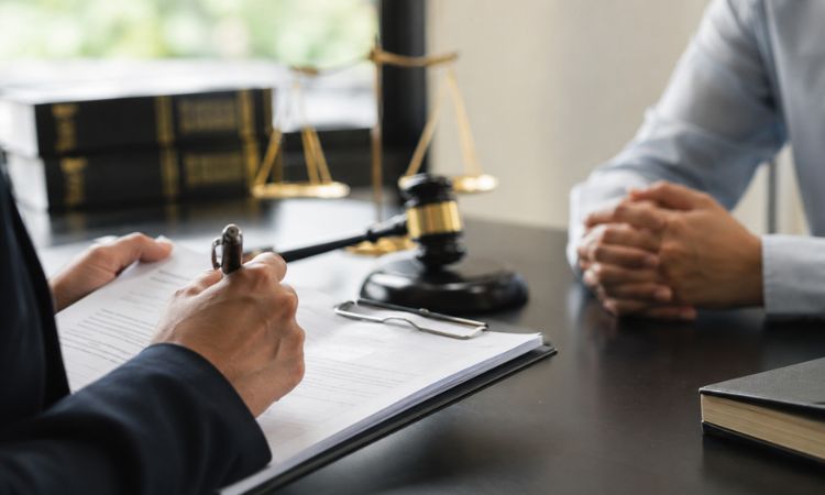 Psicólogo forense elaborando un informe pericial durante una entrevista en un contexto judicial, con documentación y elementos relacionados con la administración de justicia.